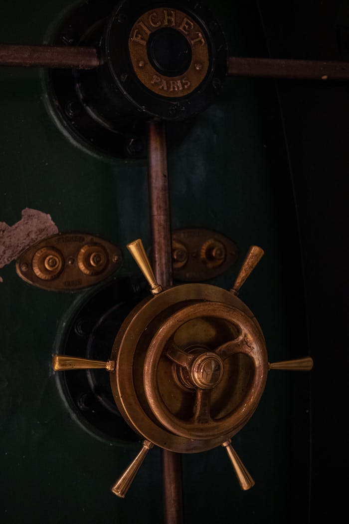 Close-up of a vintage safe door with a brass handle and dark green surface.