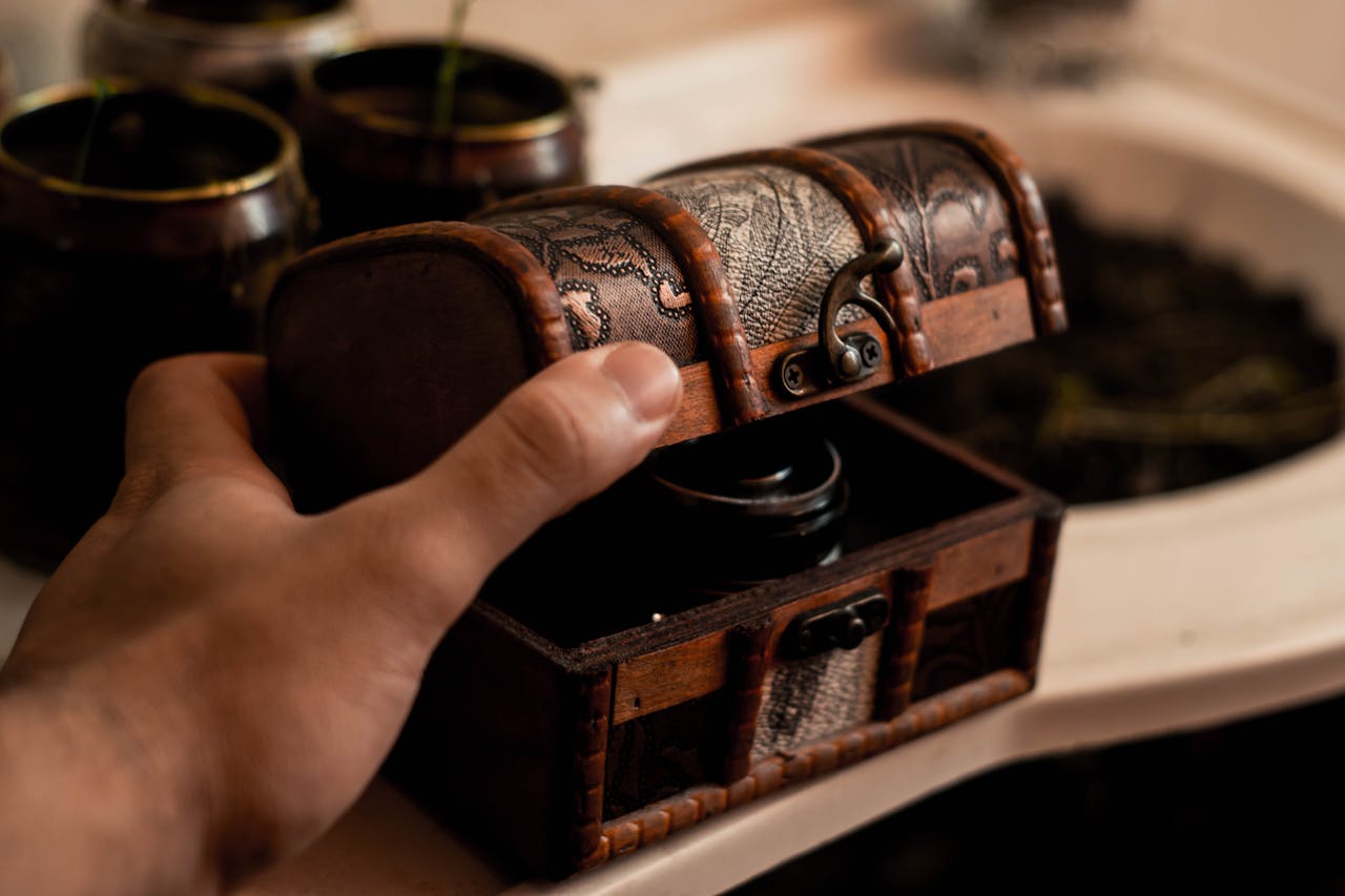 Crop anonymous male artisan opening small antique wooden chest placed on table at home