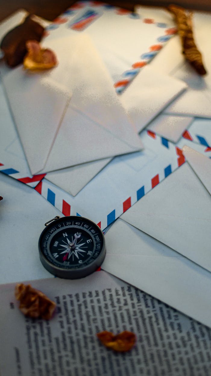 Vintage compass with airmail envelopes and dried leaves, symbolizing travel and communication.